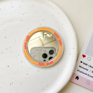 Detail des magnetischen runden Spiegels für MagSafe mit orangefarbenem Good Luck Aufdruck