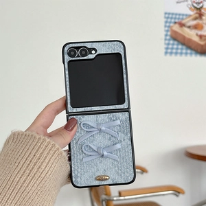 Detail of light blue textured folding phone case featuring 3D bows and gold emblem