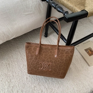 Brown leopard print tote bag with leather logo patch and slim handles on carpet