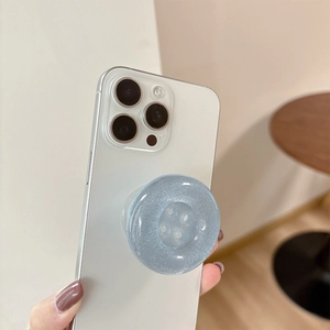 Blue glitter button style expanding phone socket grip held by a person on white background