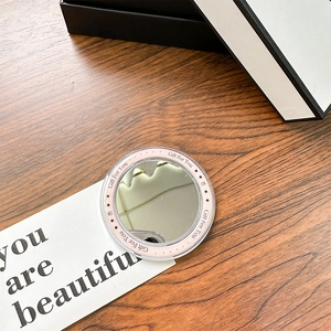Close-up of a pink magnetic makeup mirror with Gift For You text on a wooden surface