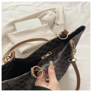 Détail de l'intérieur spacieux avec fermeture éclair et imprimé M sur le sac fourre-tout