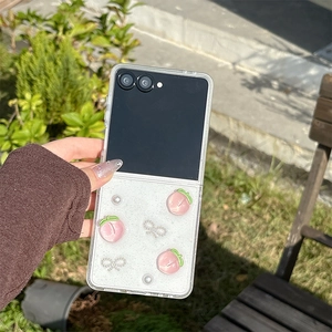 Detail of clear folding phone case with 3D peach, pearls, and a diamond bow decoration