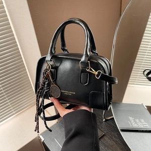 Chic black contrast Boston pillow bag with tennis racket charm and tassel detail