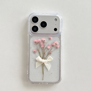 Macro detail of clear iPhone case with pink dried flowers, white ribbon, and silver glitter