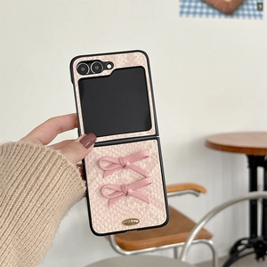 Detail of pink snakeskin texture phone case with fabric bows and gold metal plaque