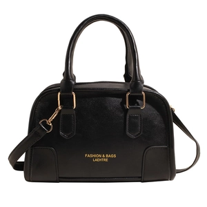 Black minimalist Boston handbag with gold hardware and shoulder strap in white background
