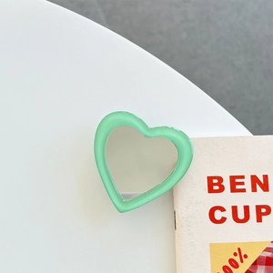Close-up of a heart-shaped mint green foldable phone socket with an integrated mirror