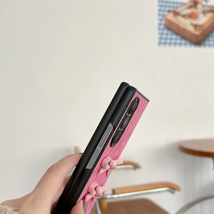 Detailed view of pink snakeskin texture phone case with 3D ribbon bows for folding phones