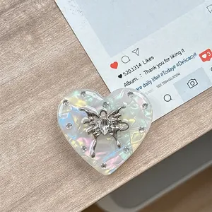 Detailansicht eines irisierenden Herz-Handyhalters mit silbernem Schmetterling und Strass