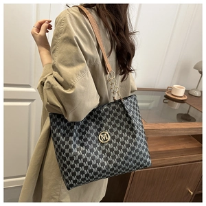 Detailed view of large tote bag with M-pattern jacquard and golden chain shoulder strap