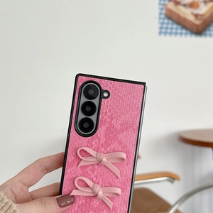 Close-up of pink snakeskin texture phone case with fabric bow decorations in hand