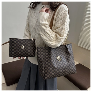 Close-up of stylish tote bag with M-pattern print and golden logo on female model