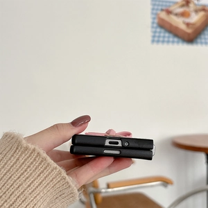 Detail of black folding phone case with pink bow accent and precise charging port cutout
