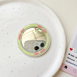 Nahaufnahme des runden MagSafe-Spiegels mit grünem Good Luck Rahmen auf einem Teller