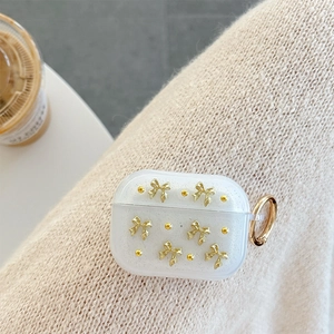 Dettaglio custodia AirPods Pro con fiocco dorato e glitter su sfondo in maglia morbida