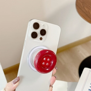 Macro shot of red button phone grip with glossy ceramic texture and pop-up stand base