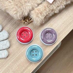 Three ink-splash button phone sockets in red, purple, and blue on a wood surface