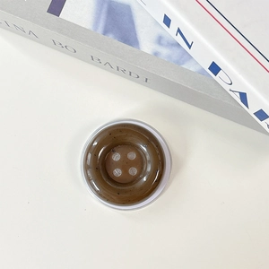 Close-up of a vintage button-shaped phone grip in amber resin on a minimalist background