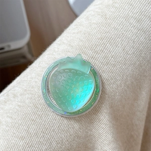 Detail of green resin strawberry phone grip with glitter base on beige knit background
