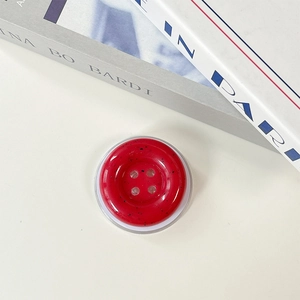 Detail of red ink-splatter button phone grip with four holes and a clear base