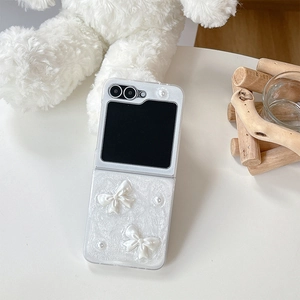 Detail of pearlescent Z Flip case with 3D white bows and pearl accents for foldable phone
