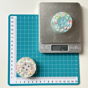 Detail view of 4cm resin buttons with glitter fruit slices on a digital scale