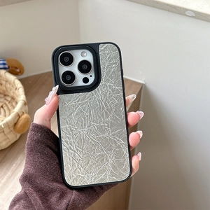 Detail showing the silver-gray crinkled paper texture and black camera lens ring on the case