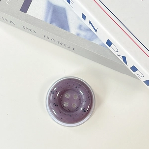 Macro shot of purple button-shaped phone grip with ink-splattered stone texture