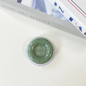 Macro detail of a green resin button phone socket with artistic black ink splash texture