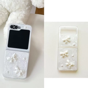 Detail of Galaxy Z Flip case featuring 3D bows and pearls on a white pearlescent finish