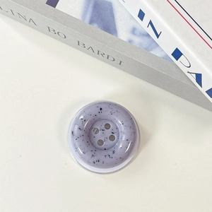 Detail view of purple ink splash button phone grip with terrazzo texture on white desk
