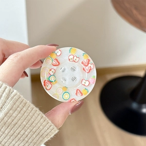 Close-up of circular fruit-themed glitter phone grip with strawberry and lemon prints