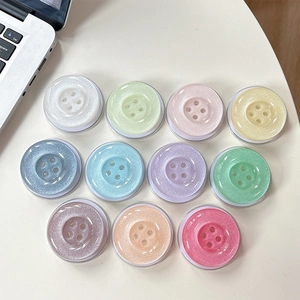 Detailed view of colorful glitter button phone grips arranged neatly on a white desk