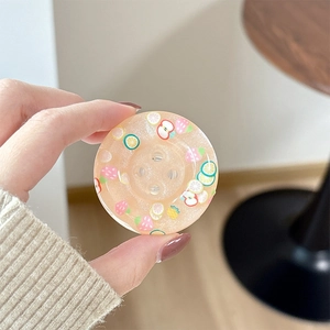 Close-up of glitter resin phone grip with colorful fruit illustrations and button design