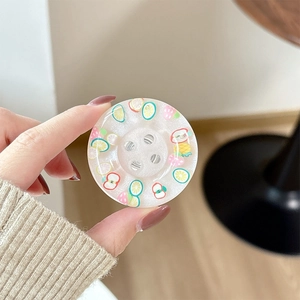Detail of glitter resin button phone grip featuring colorful fruit pattern accents