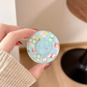 Close-up of glittery blue resin phone grip with colorful fruit slice patterns in hand