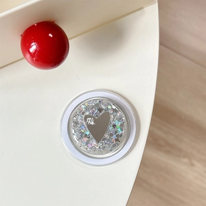 Macro view of a round sequin phone grip with a heart mirror and silver glitter interior