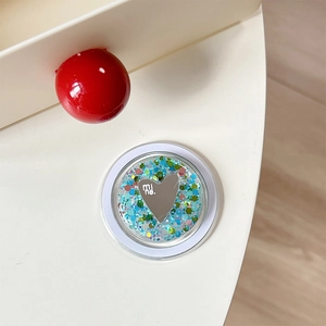 Macro view of a round sequin phone grip featuring a silver heart with mine. engraving
