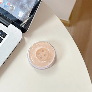 Macro shot of button-shaped phone grip with glitter finish on a white table