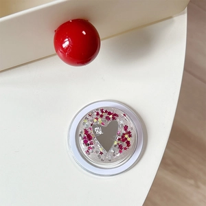 Detail of a round foldable phone grip with a heart mirror and floating colorful sequins