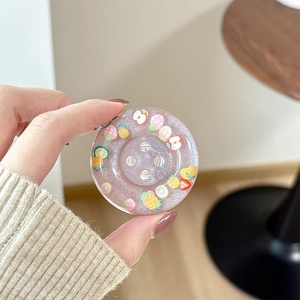 Close-up of a pink glitter resin phone grip featuring cute cartoon fruit patterns