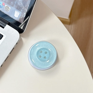 Detailed close-up of light blue glitter button phone socket on a minimalist white desk