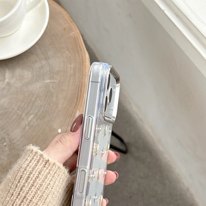 Detail showing transparent iPhone case with silver camera frame and sparkling sequins