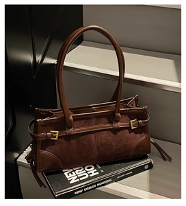 Detail of dark brown tote bag with suede texture, stitching, and metal buckle accents
