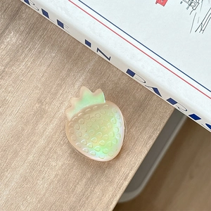 Iridescent strawberry phone grip with holographic effect on a wooden table setup