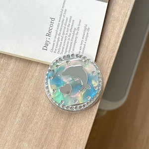 Close-up of a rhinestone magnetic phone grip with silver dolphin and heart mirror design