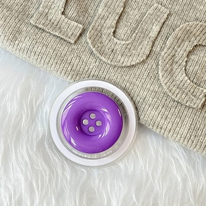 Detail der kreativen violetten Knopfform Magnethalterung auf weißem Kunstfellhintergrund