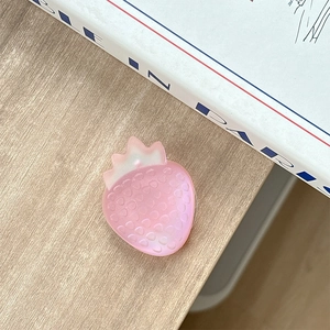 Detailed macro of a matte pink resin strawberry phone socket on a wooden desk setup