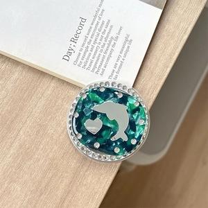 Detail of green marble phone grip featuring a silver dolphin heart and rhinestones